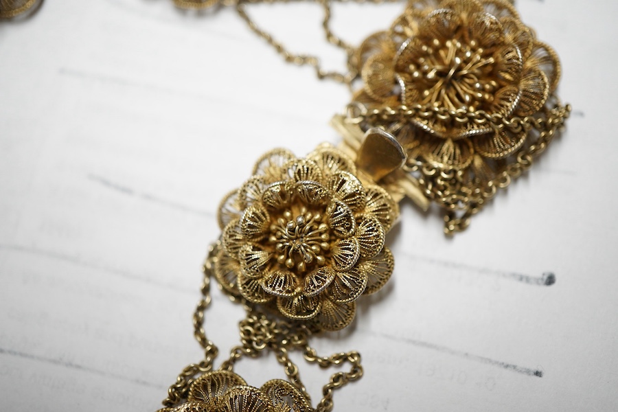A gilt white metal filigree parure, comprising a necklace, 36cm, with flower head motifs, a pair of flower head earrings and a bracelet.